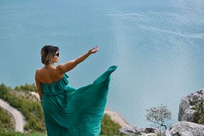 Woman standing by sea against blue sky