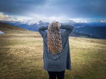 Rear view of woman standing on field against sky