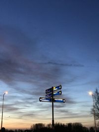 Low angle view of illuminated sign against sky at sunset
