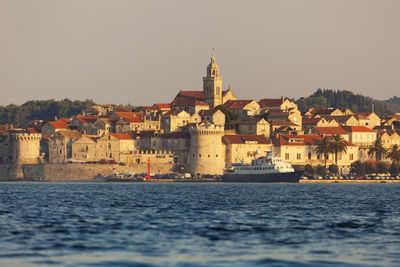 Buildings by sea against clear sky