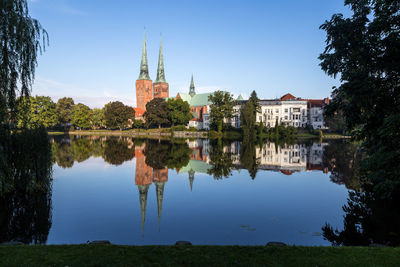 Reflection of buildings and trees in lake against sky