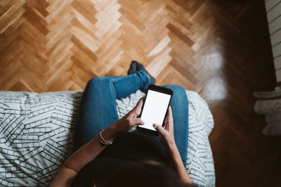 Low section of pregnant woman using phone while resting at home