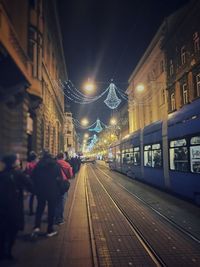 Illuminated railroad station in city against sky at night