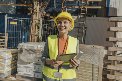 Smiling woman supervisor using digital tablet while standing at construction site
