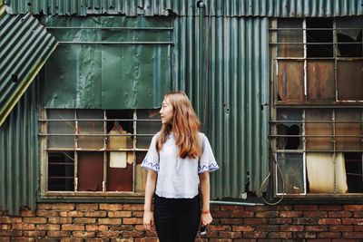 Woman with umbrella standing against brick wall