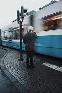 Rear view of man standing at railroad station