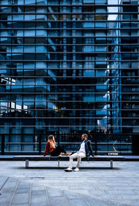 People sitting against modern building in city