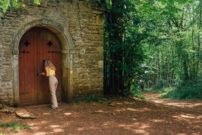 Rear view of woman looking in church in forest. woman standing by door of building 