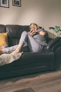 Full length of young man sitting on sofa at home