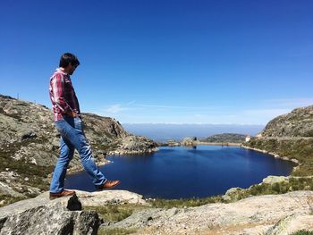 Man standing on rock at torre mountain by lake against sky