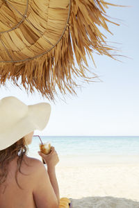 Midsection of woman on beach against sky