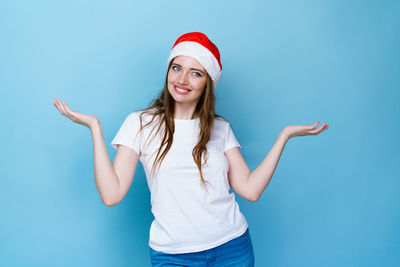 Portrait of smiling young woman against blue background