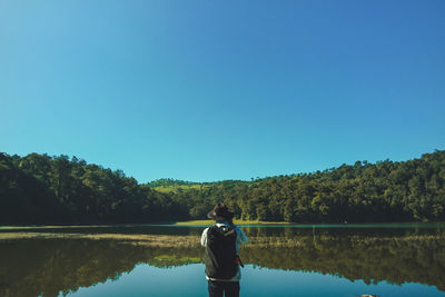 Rear view of man looking at lake against sky