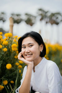 Portrait of smiling girl standing against yellow flowering plants