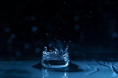Close-up of splashing droplet in blue water against black background