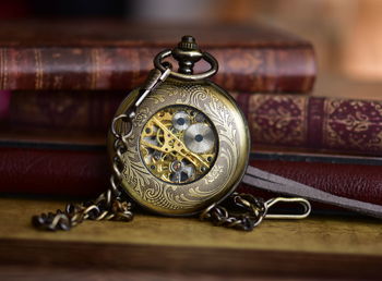 Close-up of antique pocket watch by books on table