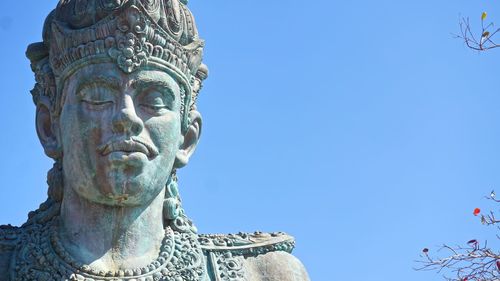 Low angle view of male statue against clear blue sky