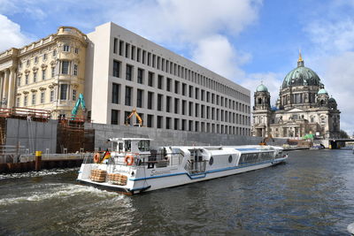 Boats in canal by buildings against sky