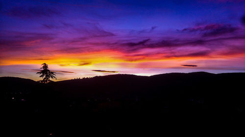 Silhouette landscape against orange sky