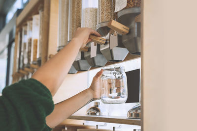 Customer filling lentils in glass jar at zero waste shop