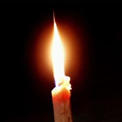 Close-up of burning candle in darkroom