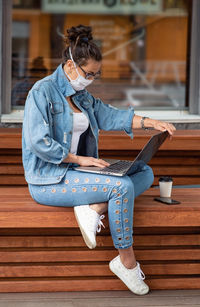 Full length of woman using laptop outdoors