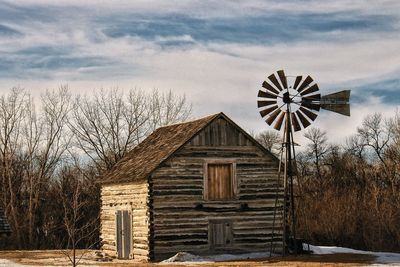 American-style windmill outside old house against sky