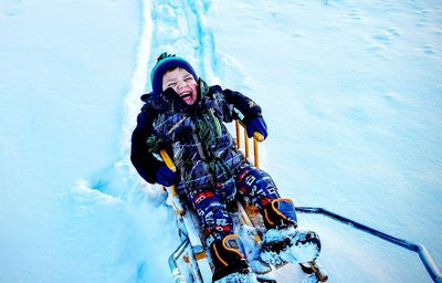 High angle view of happy boy on sled