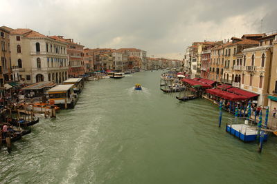 Boats in canal amidst buildings in city against sky