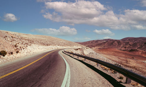 Road leading towards mountain against sky