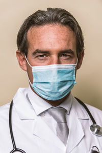 Portrait of doctor wearing mask against colored background