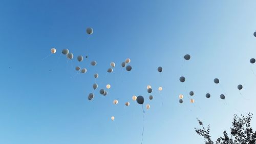 Low angle view of balloons flying against clear blue sky