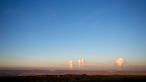 Factory on field against clear sky at sunset