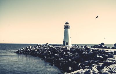 View of lighthouse by sea against clear sky