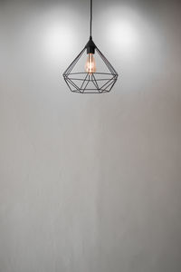 Close-up of illuminated light bulb hanging on wall