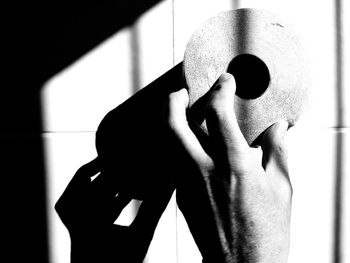 Midsection of person holding umbrella standing against wall