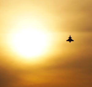 Low angle view of silhouette bird flying against sky during sunset