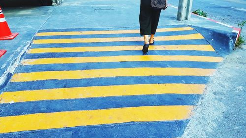 Low section of person walking on zebra crossing