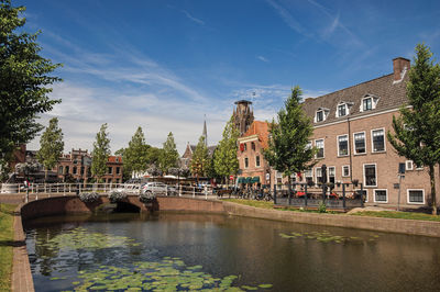 Bridge over river by buildings against sky in city