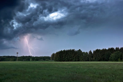 Scenic view of lightning over landscape against dramatic sky