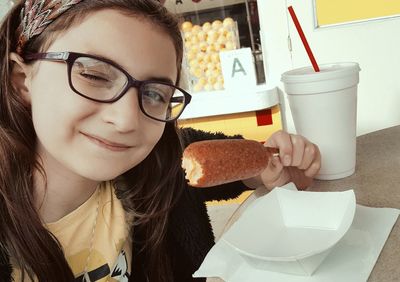 Portrait of girl winking while having food at restaurant