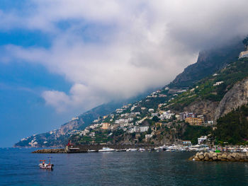 Scenic view of sea by mountain against sky