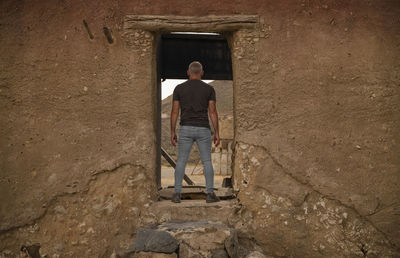 Rear view of man sitting on wall