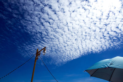 White fluffy clouds in the bright blue sky with glare and bright light of sun