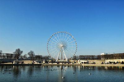 Ferris wheel at amusement park against clear blue sky