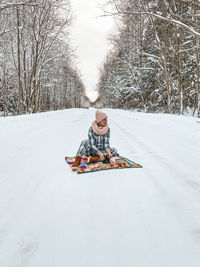 Girl sitting on snow covered field