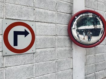 Reflection of people on road mirror attached to wall