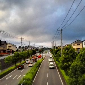 Cars moving on road against cloudy sky