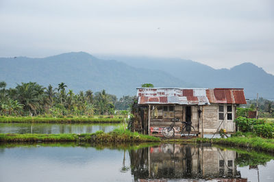 House by lake against sky