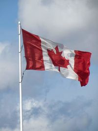 High section of canadian flag against clouds